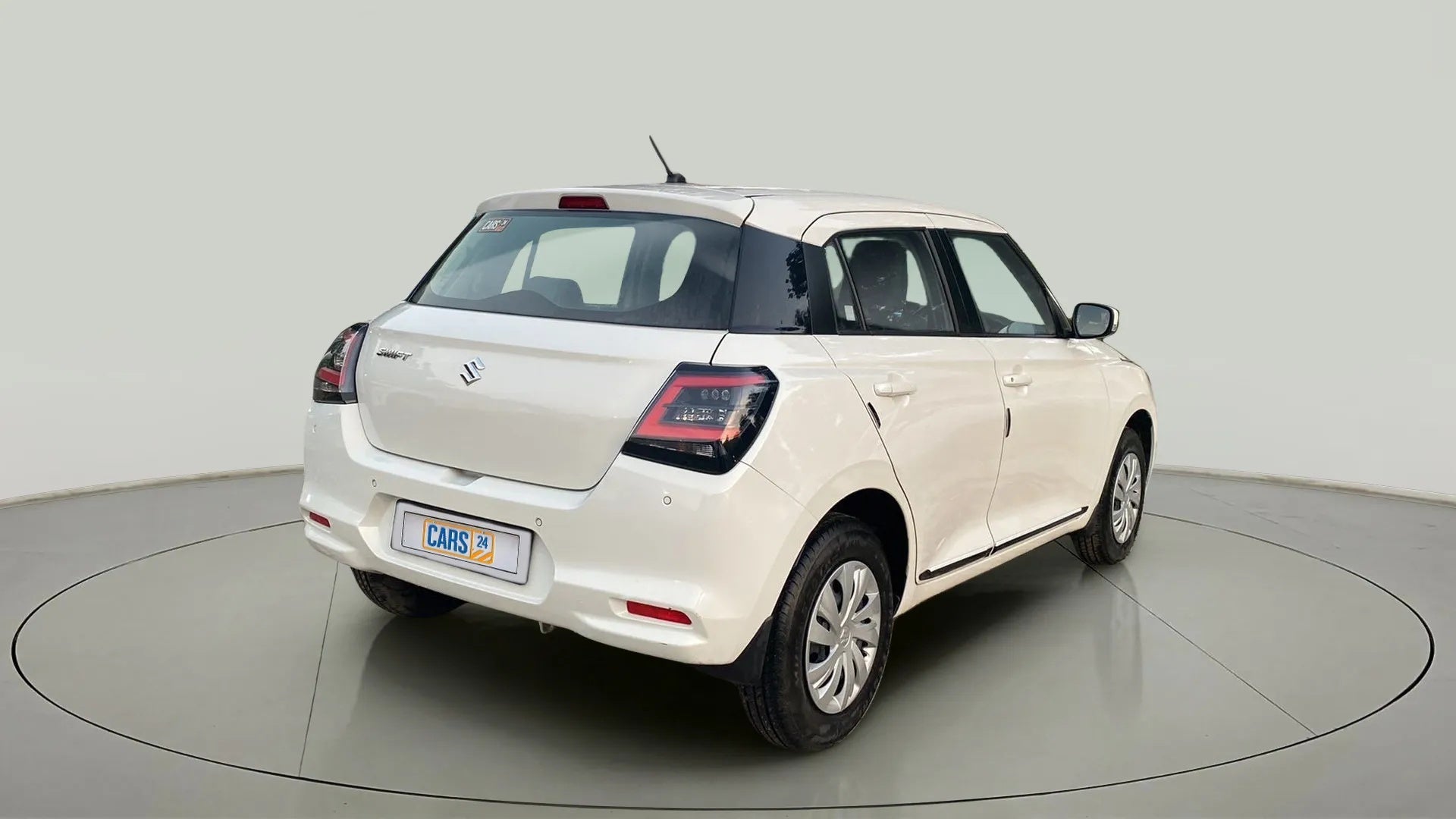 Rear three-quarter view of a Pearl Arctic White with Pearl Midnight Black Maruti Suzuki Swift