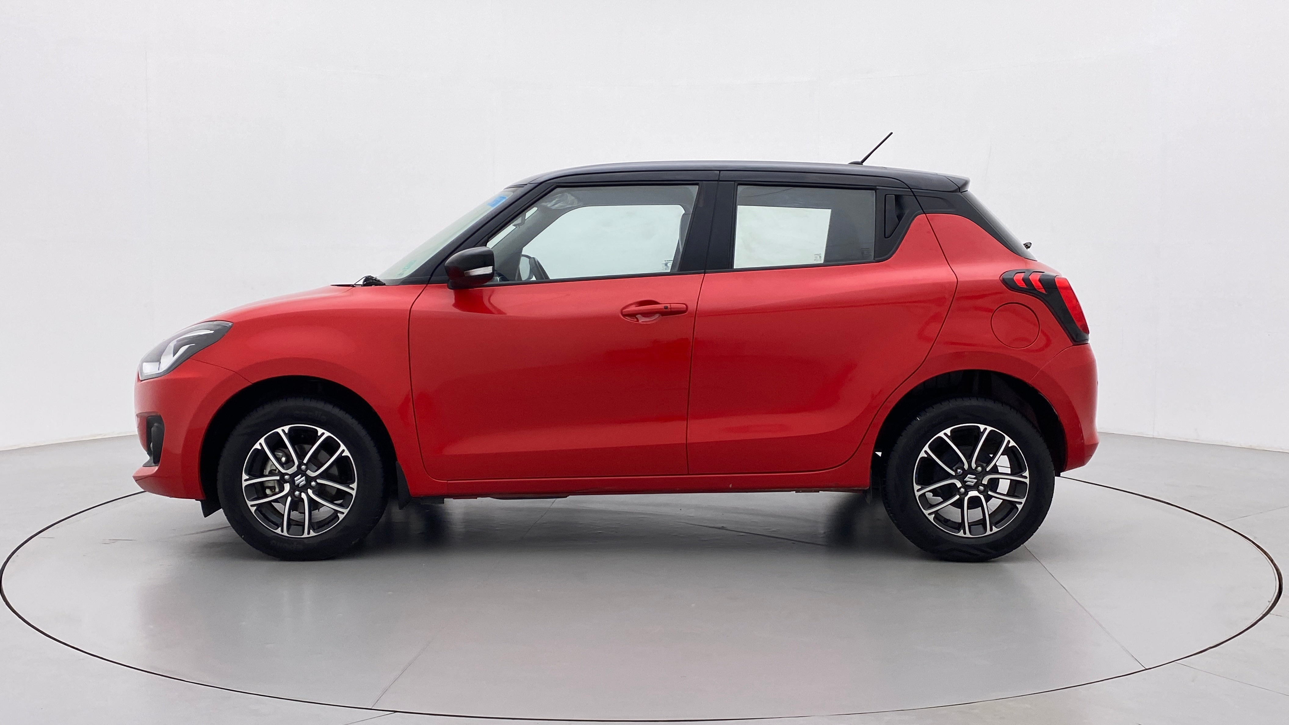 Side view of a solid fire red with pearl midnight black roof Maruti Suzuki Swift 2021 - 2023