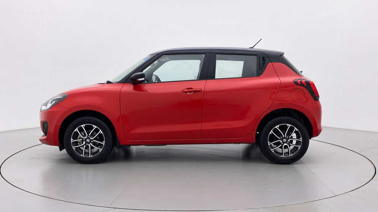 Side view of a solid fire red with pearl midnight black roof Maruti Suzuki Swift 2021 - 2023