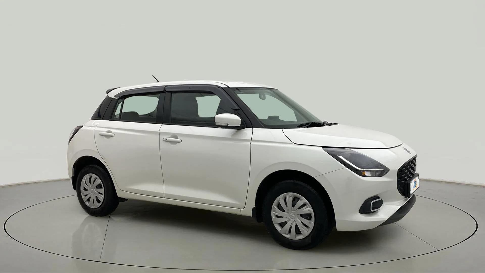 Front and side view of a pearl arctic white with pearl midnight black Maruti Suzuki Swift