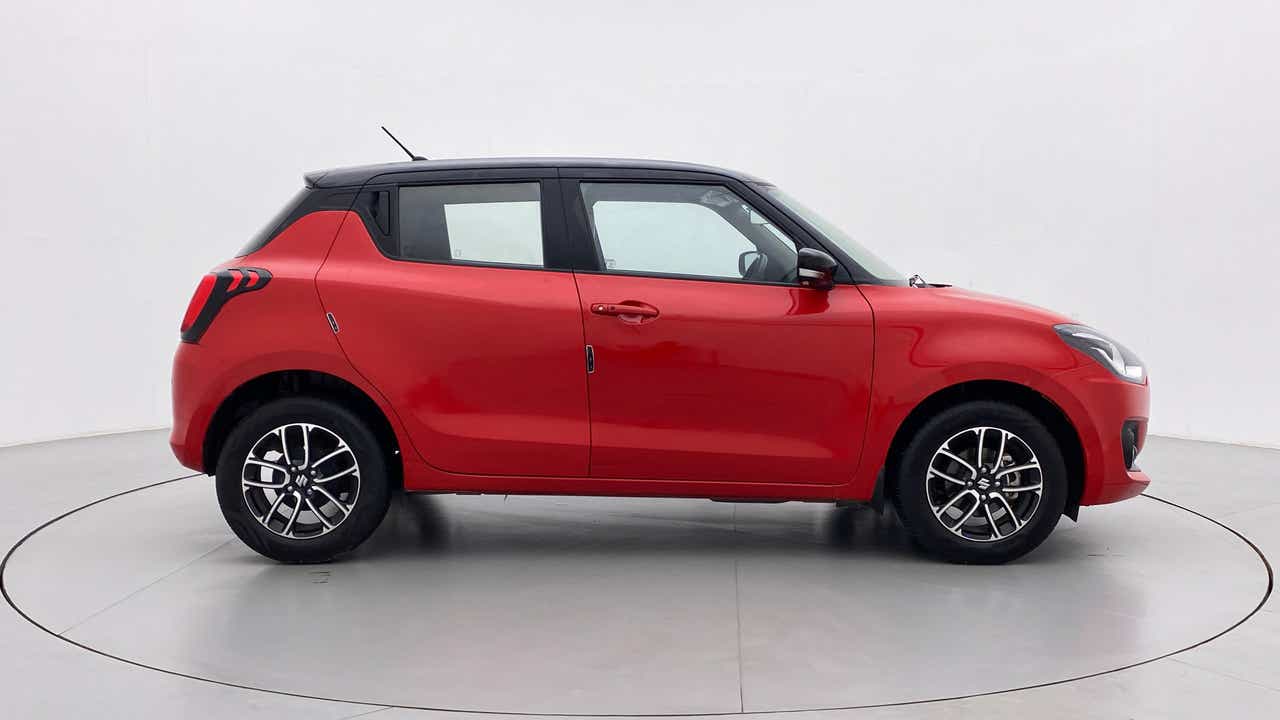 Side view of a solid fire red with pearl midnight black roof Maruti Suzuki Swift 2021 - 2023