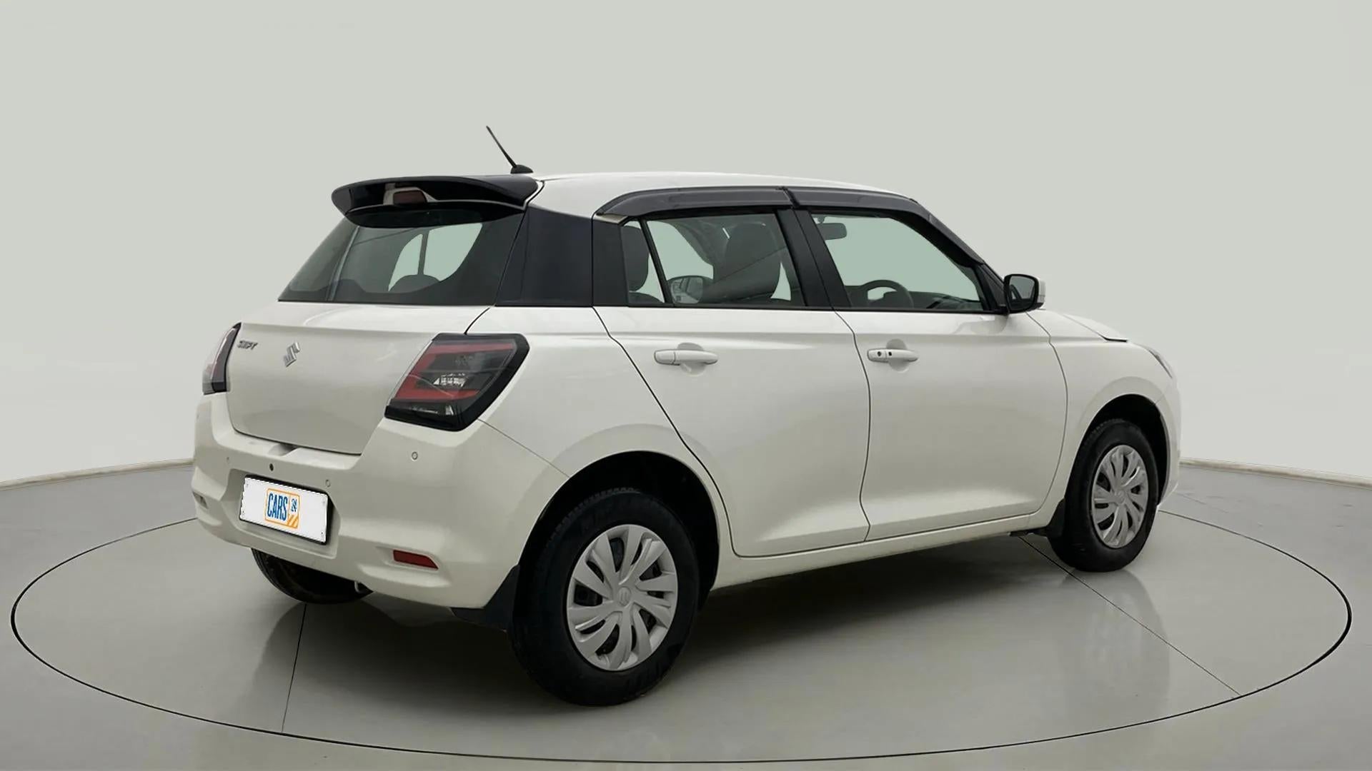 Rear three-quarter of a Pearl Arctic White with Pearl Midnight Black Maruti Suzuki Swift