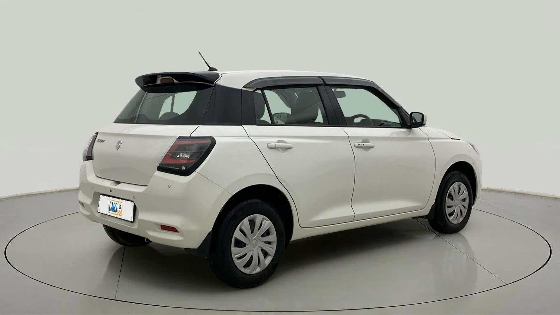 Rear three-quarter of a Pearl Arctic White with Pearl Midnight Black Maruti Suzuki Swift