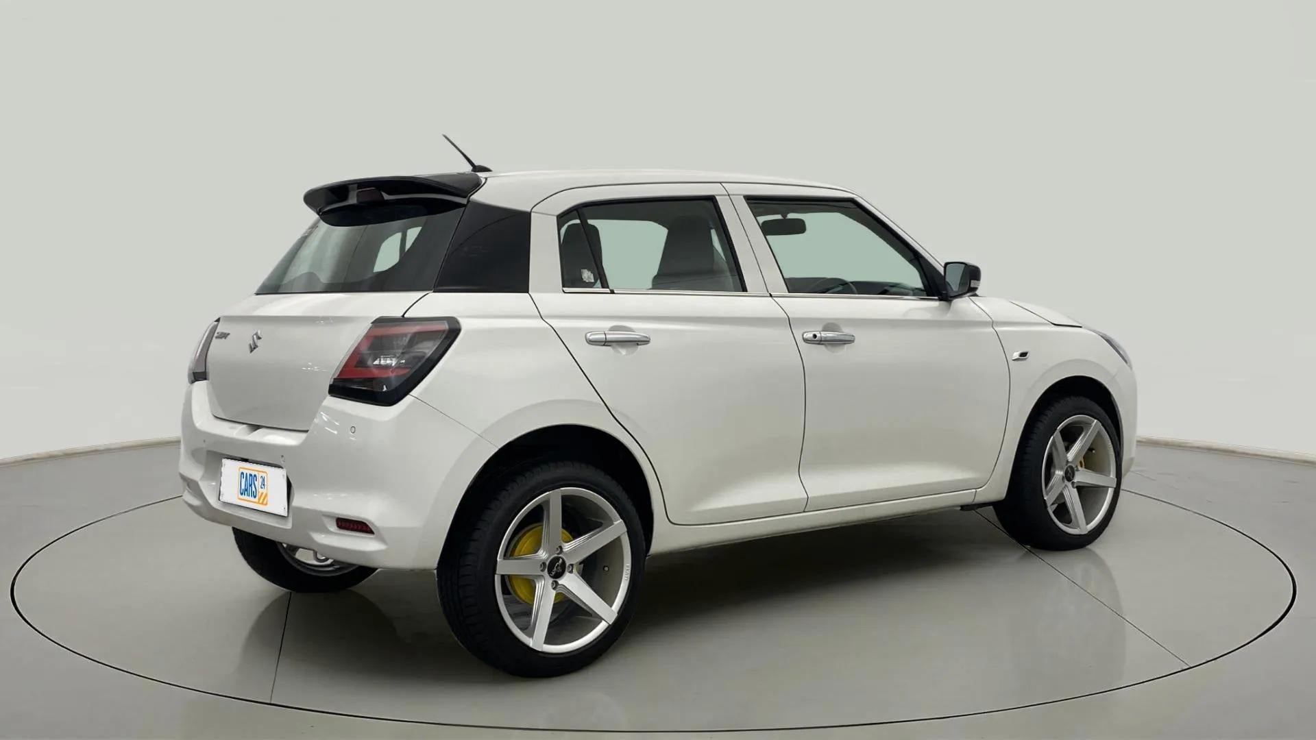 Rear three-quarter view of a Pearl Arctic White with Pearl Midnight Black Maruti Suzuki Swift