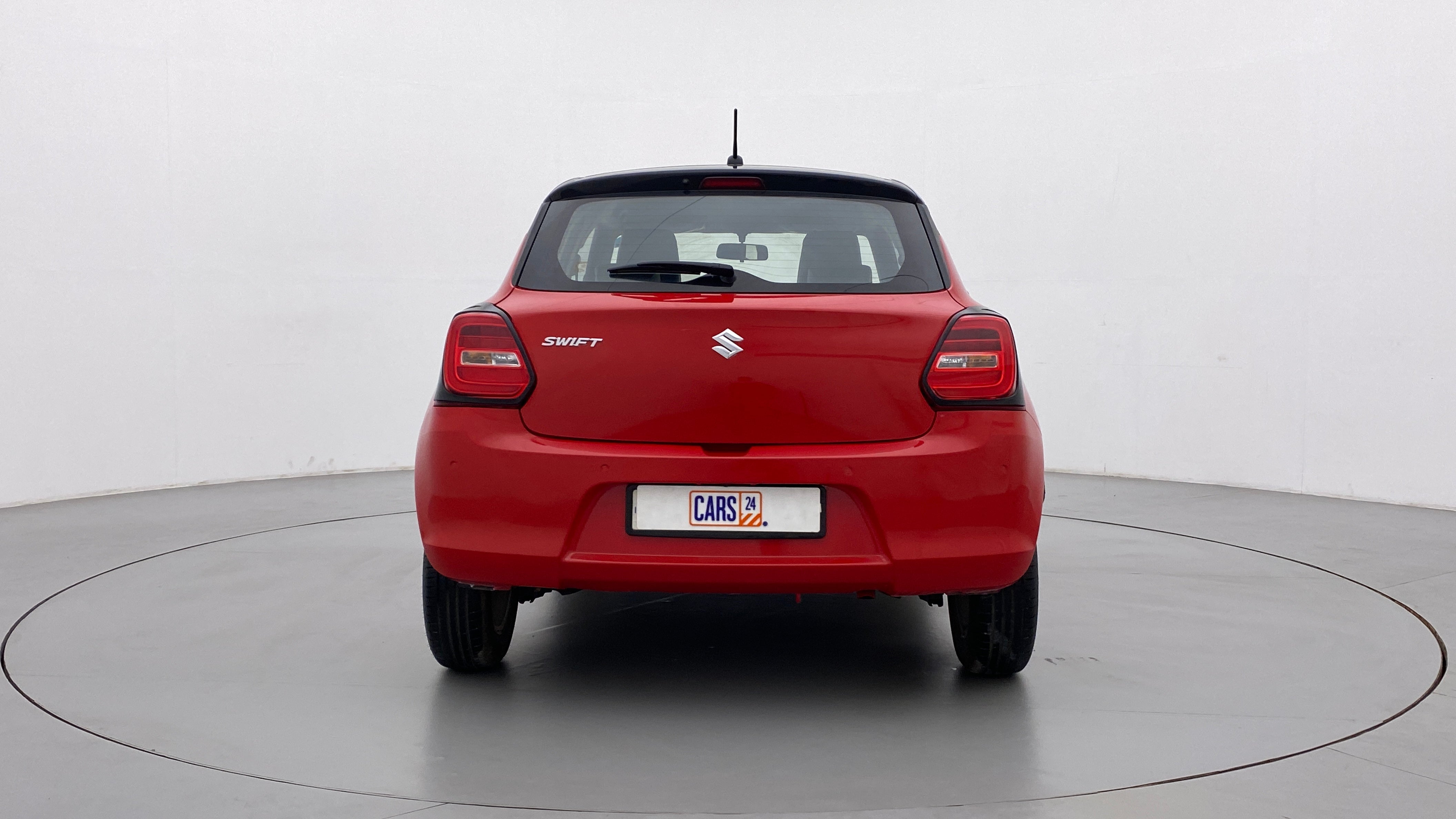 Rear view of a solid fire red with pearl midnight black roof Maruti Suzuki Swift 2021 - 2023