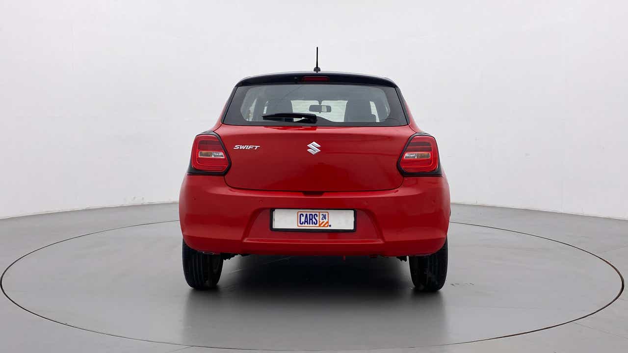 Rear view of a solid fire red with pearl midnight black roof Maruti Suzuki Swift 2021 - 2023