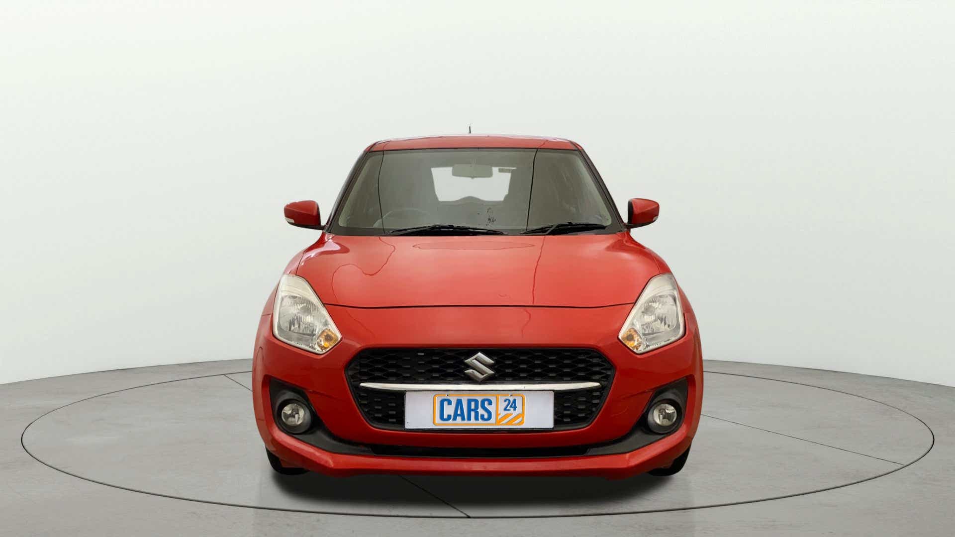 Front view of a solid fire red Maruti Suzuki Swift 2021 - 2023