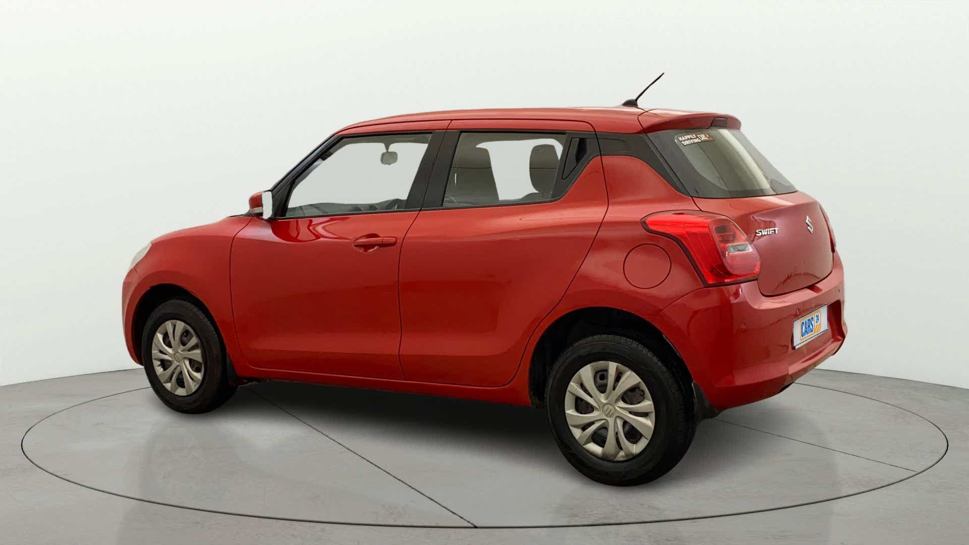 Rear three-quarter view of a solid fire red Maruti Suzuki Swift 2021 - 2023