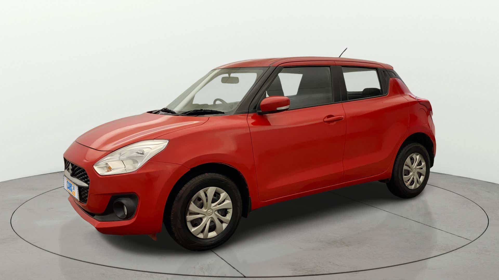 Front three-quarter view of a solid fire red with pearl midnight black roof Maruti Suzuki Swift 2021 - 2023