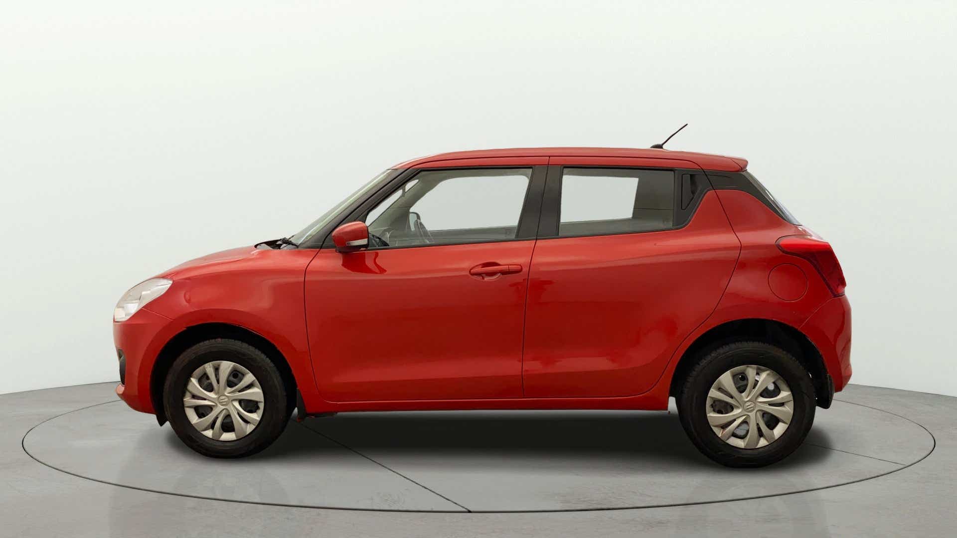 Side view of a solid fire red Maruti Suzuki Swift 2021 - 2023
