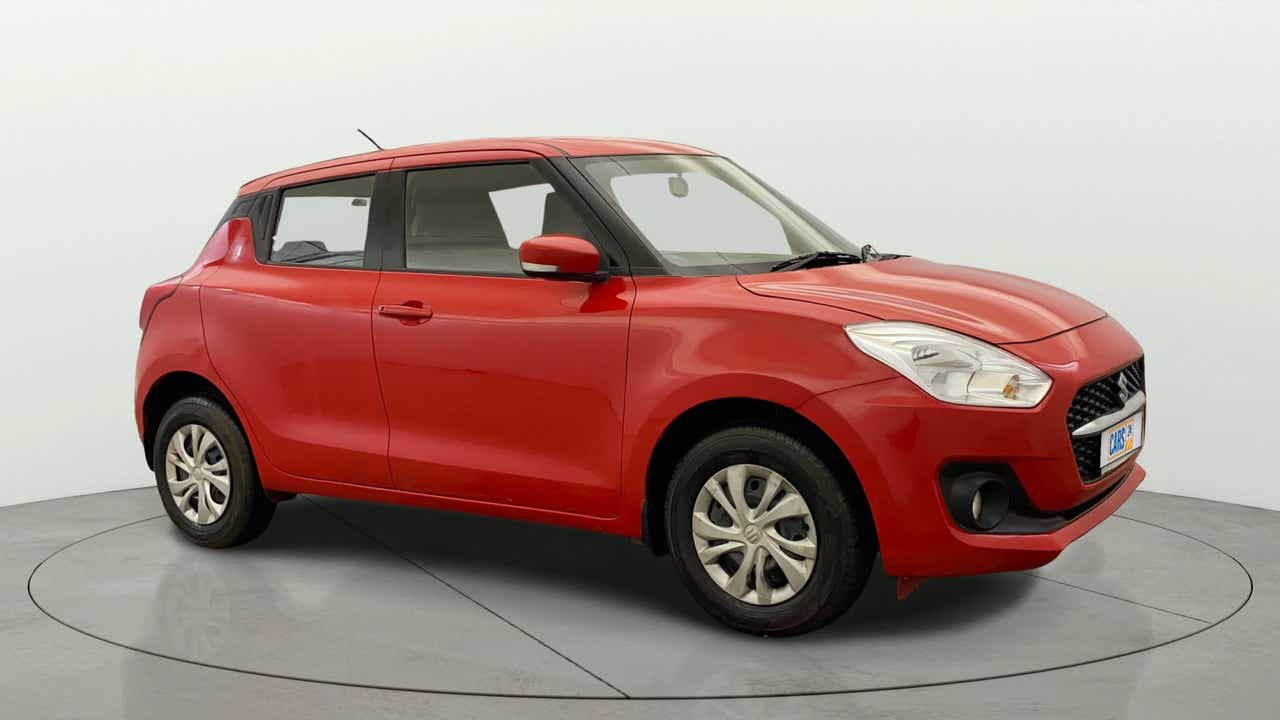 Front side view of a solid fire red Maruti Suzuki Swift 2021 - 2023