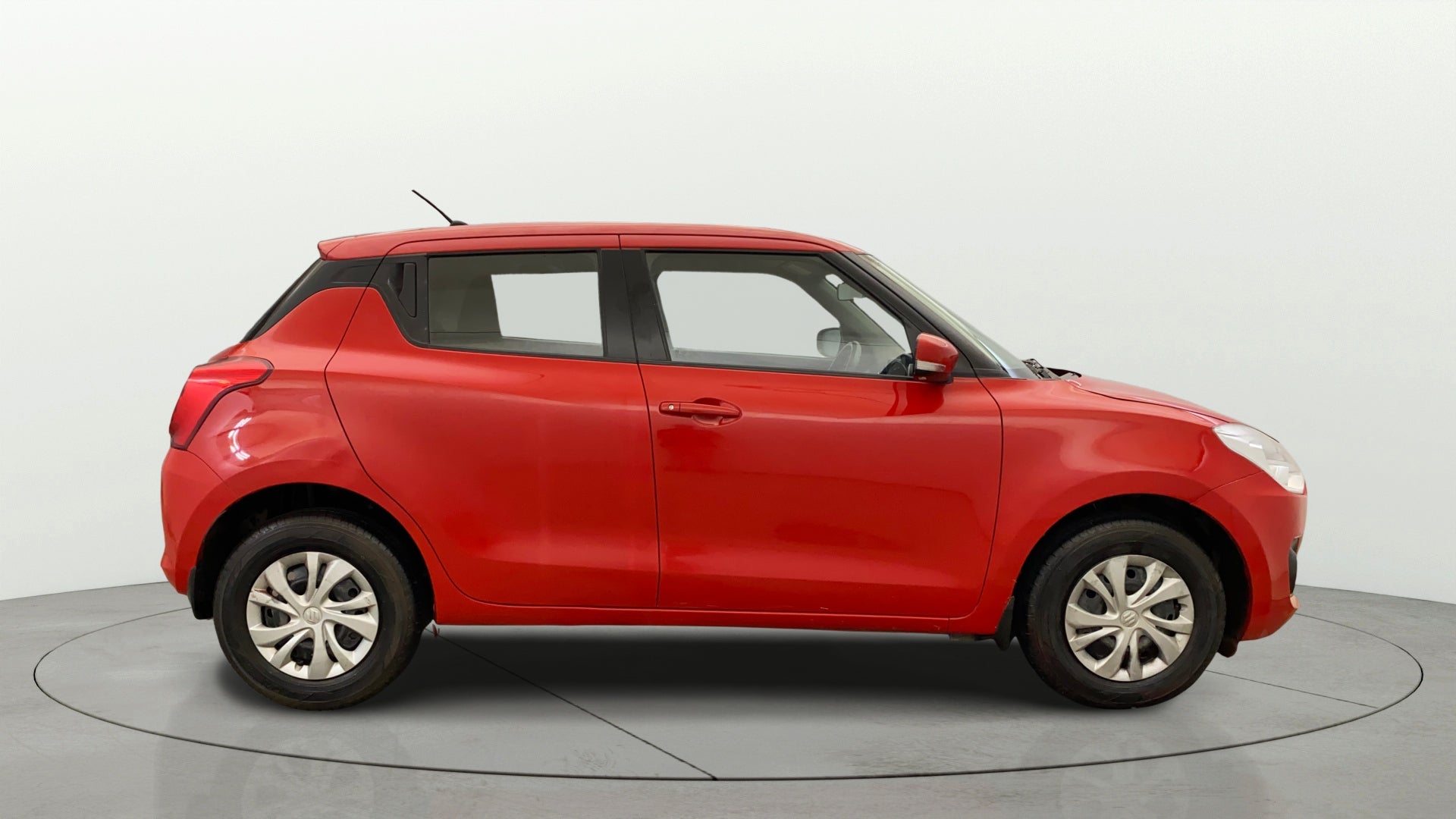 Side view of a solid fire red with pearl midnight black roof Maruti Suzuki Swift 2021 - 2023