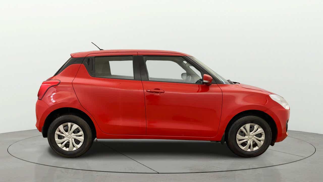 Side view of a solid fire red with pearl midnight black roof Maruti Suzuki Swift 2021 - 2023