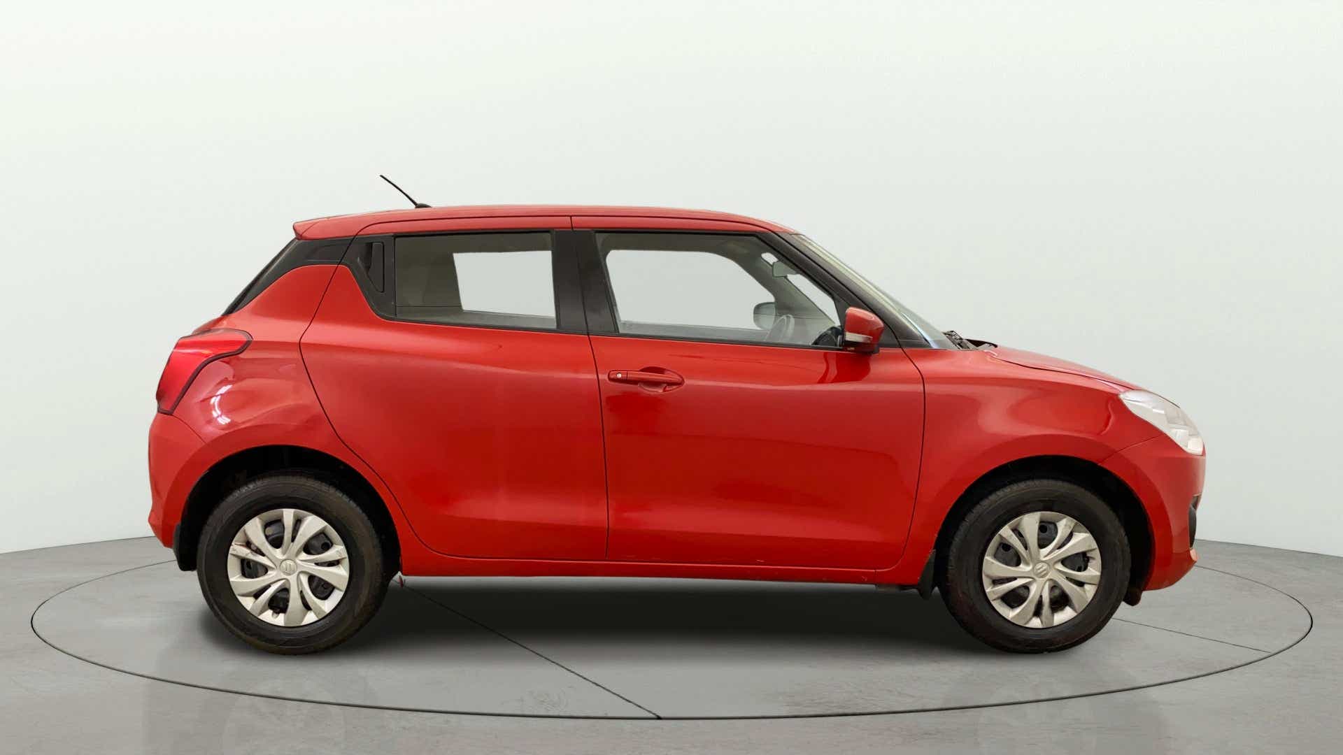 Side view of a solid fire red with pearl midnight black roof Maruti Suzuki Swift 2021 - 2023