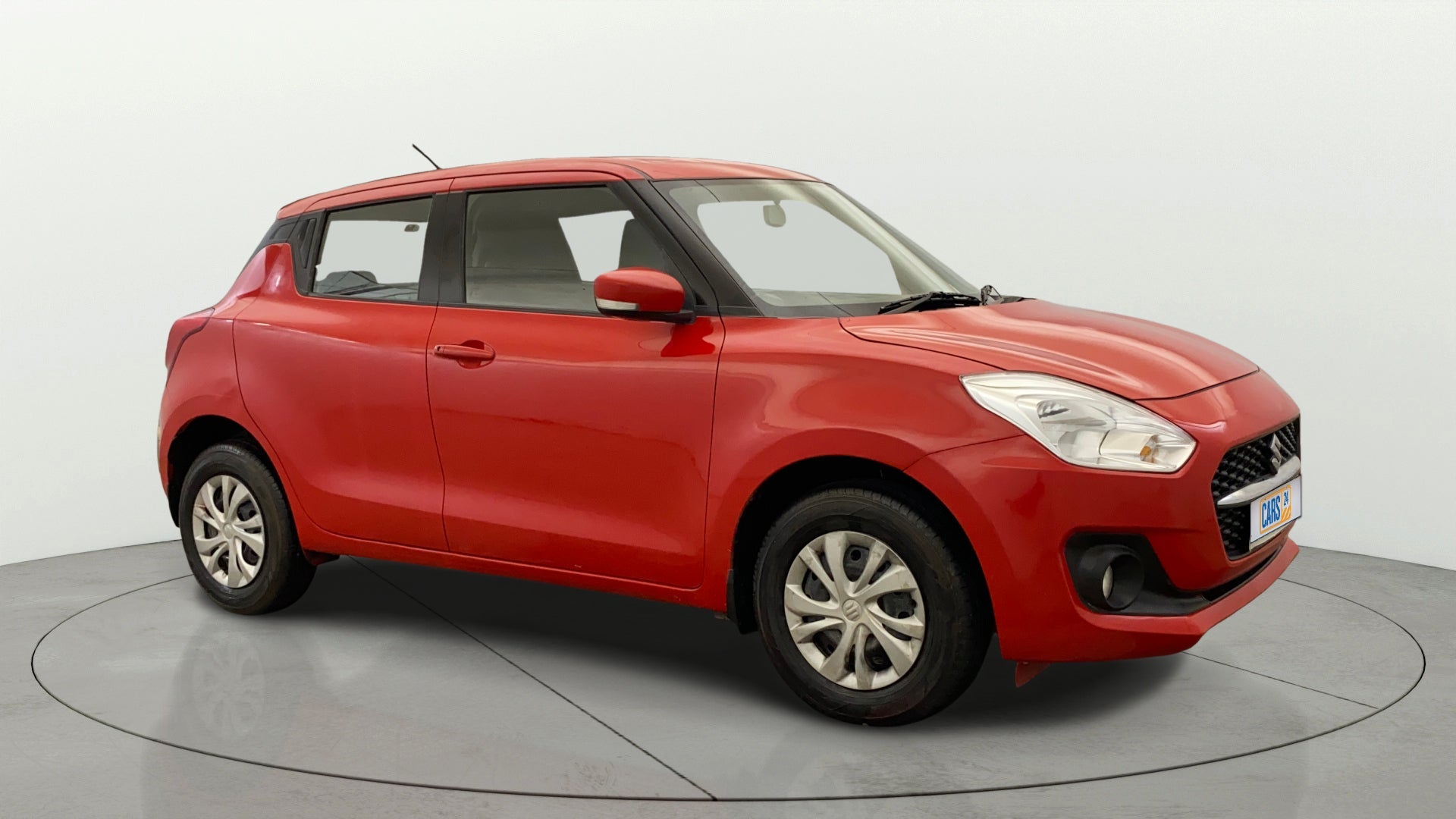 Front-side view of a solid fire red Maruti Suzuki Swift 2021 - 2023