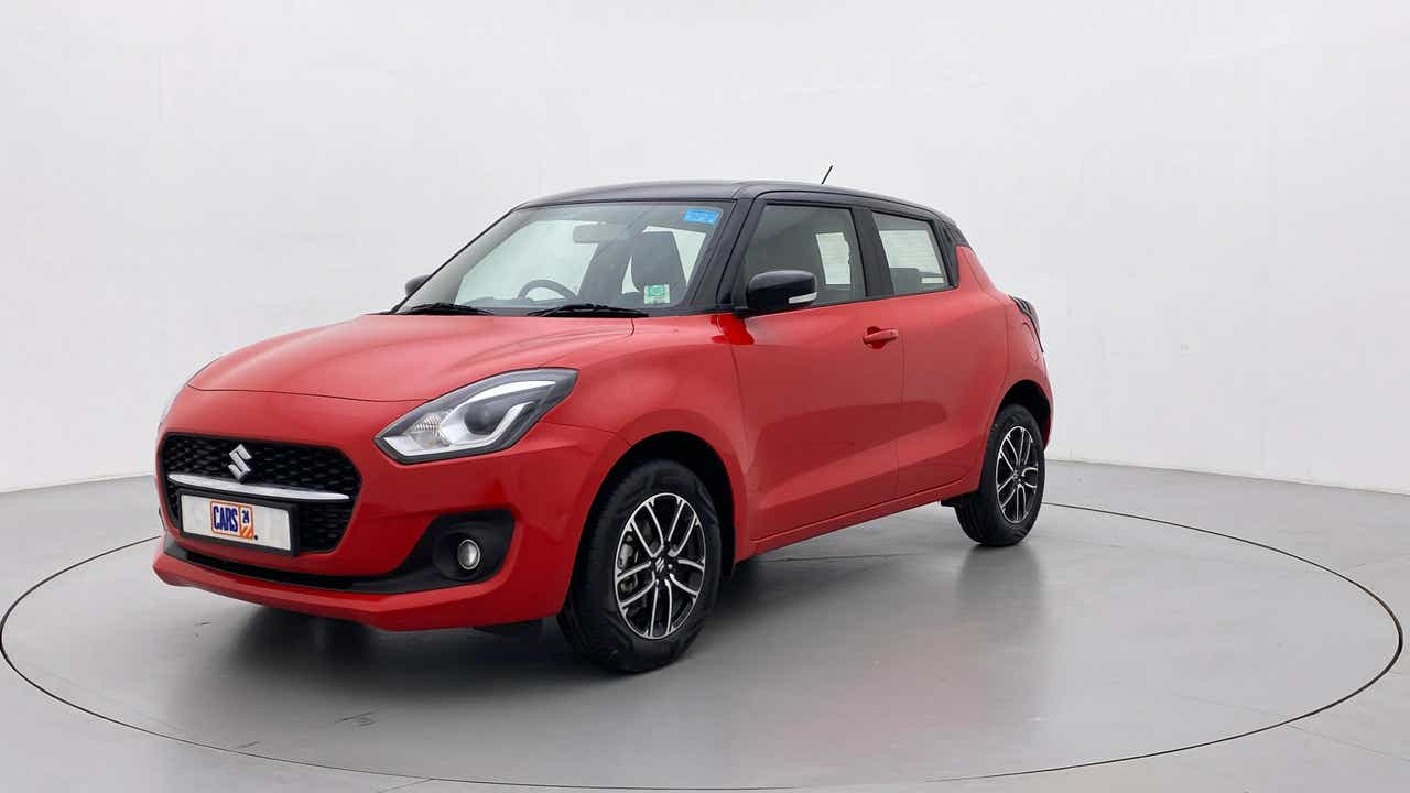 Front three-quarter view of a solid fire red with pearl midnight black roof Maruti Suzuki Swift 2021 - 2023
