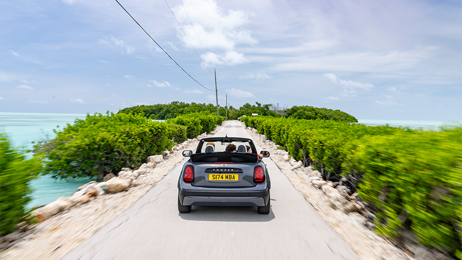 Rear view of a Mini Cooper S Convertible driving on a scenic road