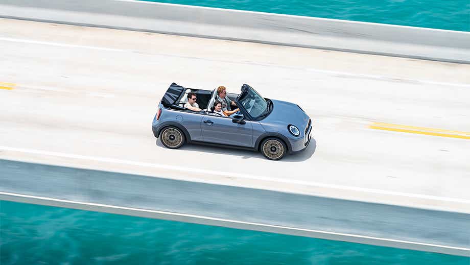 Side view of a Mini Cooper S Convertible driving on a bridge