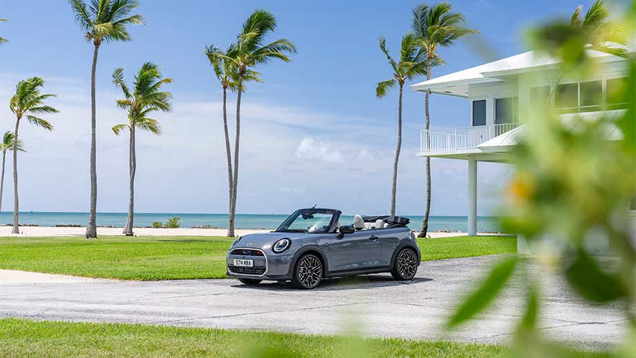 Front three quarter view of a Mini Cooper S Convertible parked near a beach house