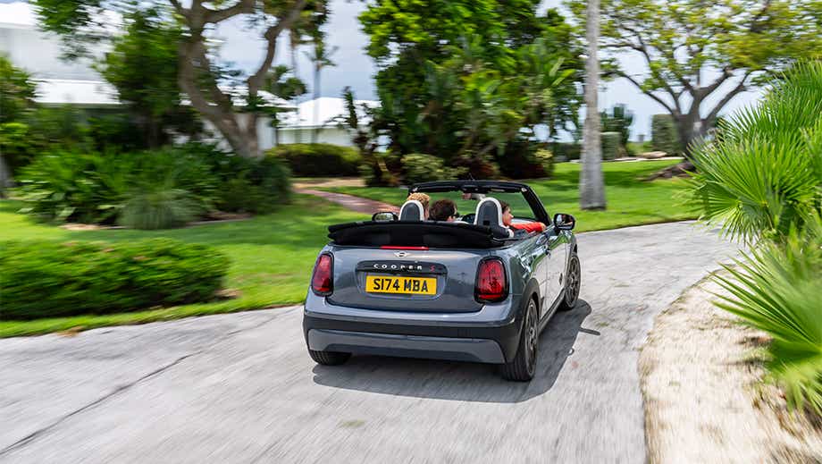 Rear view of a Mini Cooper S Convertible driving on a scenic road