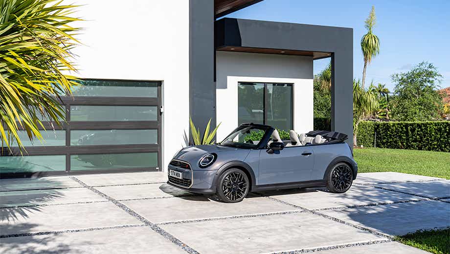 Front three-quarter of a Mini Cooper S Convertible parked outside a modern house