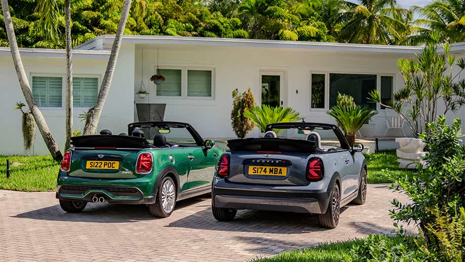 Rear view of a british racing green mini cooper s convertible and another mini cooper s convertible