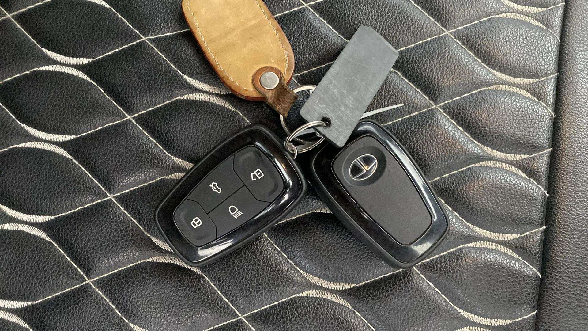 Close-up of a tata punch key fob and remote on black stitched seat