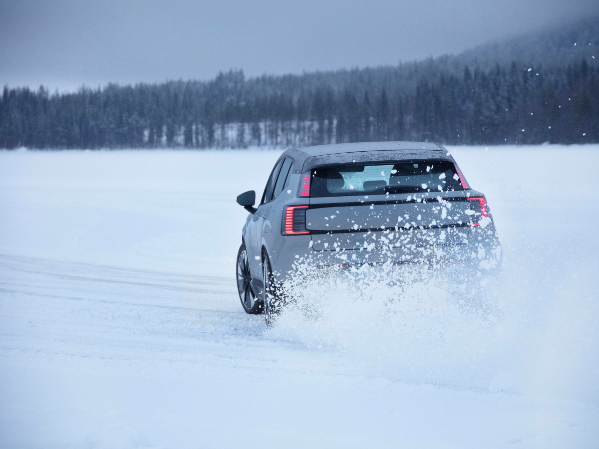 Rear view of a vapour grey Volvo EX30 driving on snow