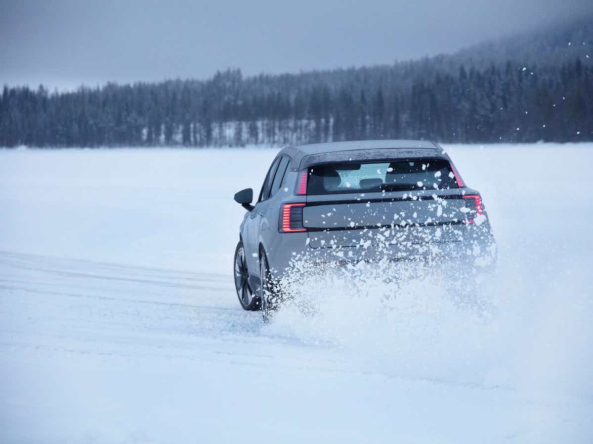Rear view of a vapour grey Volvo EX30 driving on snow