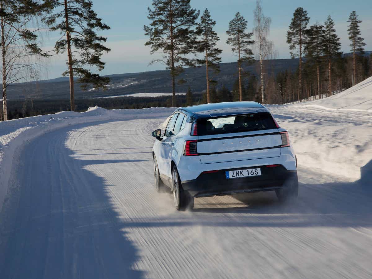 Rear view of a cold blue Volvo EX30 on a snowy road